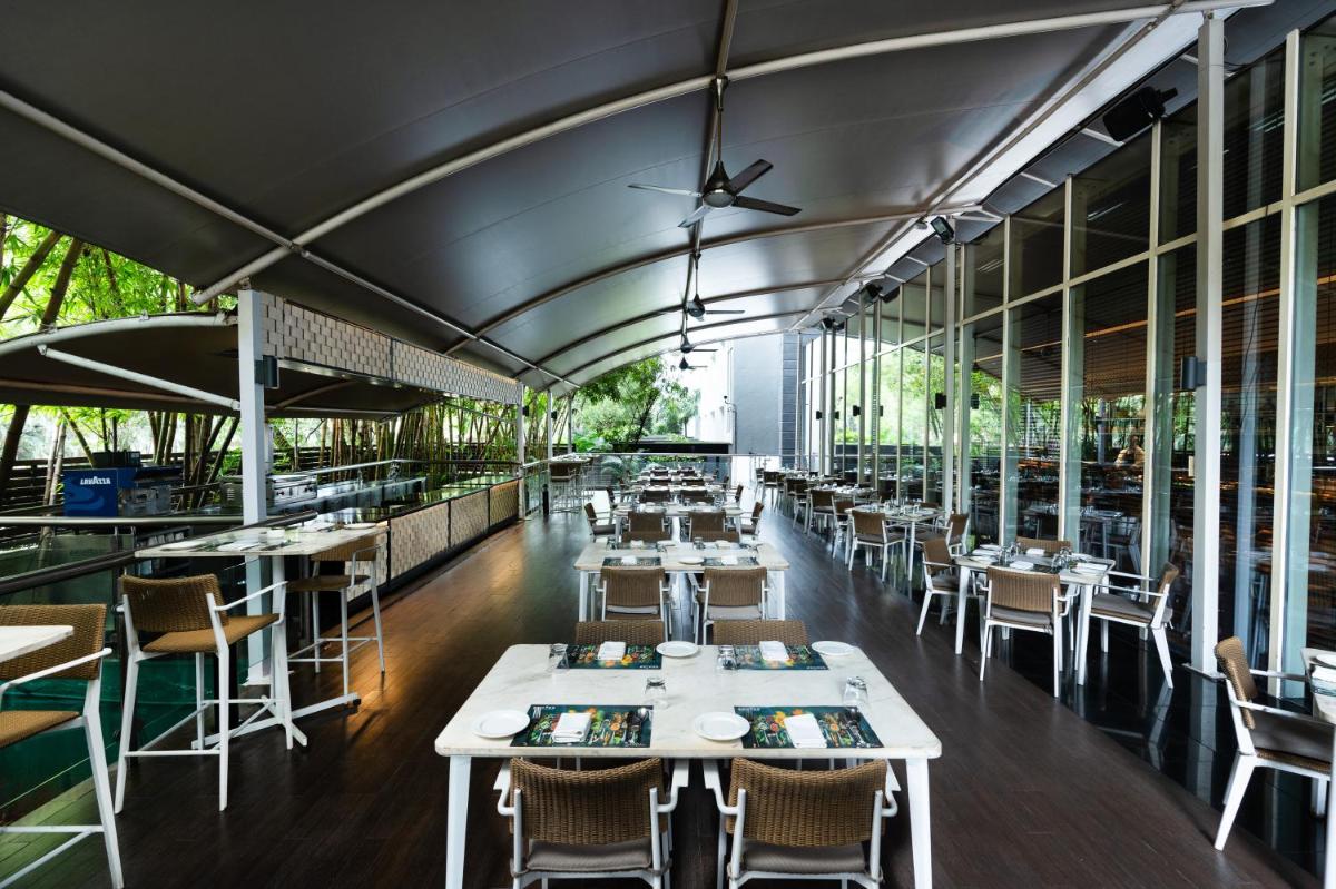 a restaurant with white tables and chairs and windows at Marriott Suites Pune in Pune