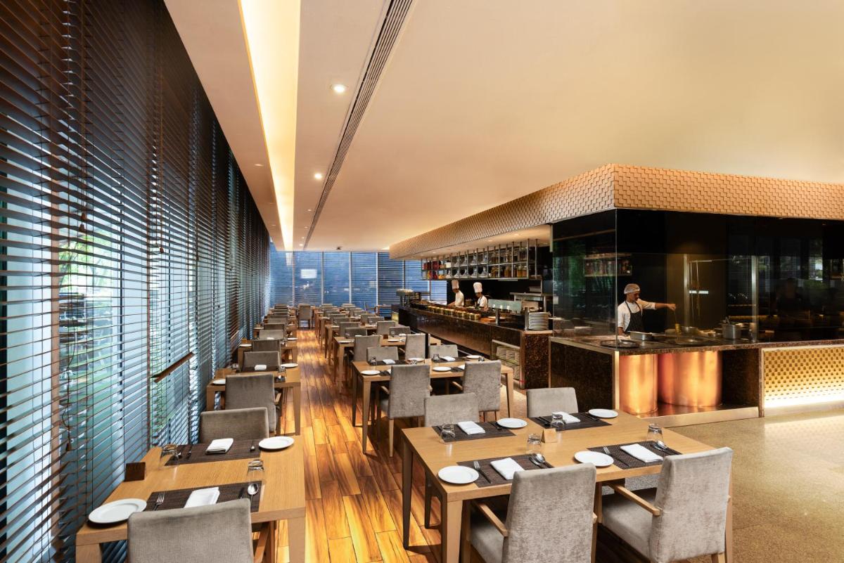 a restaurant with wooden tables and chairs and a bar at Marriott Suites Pune in Pune