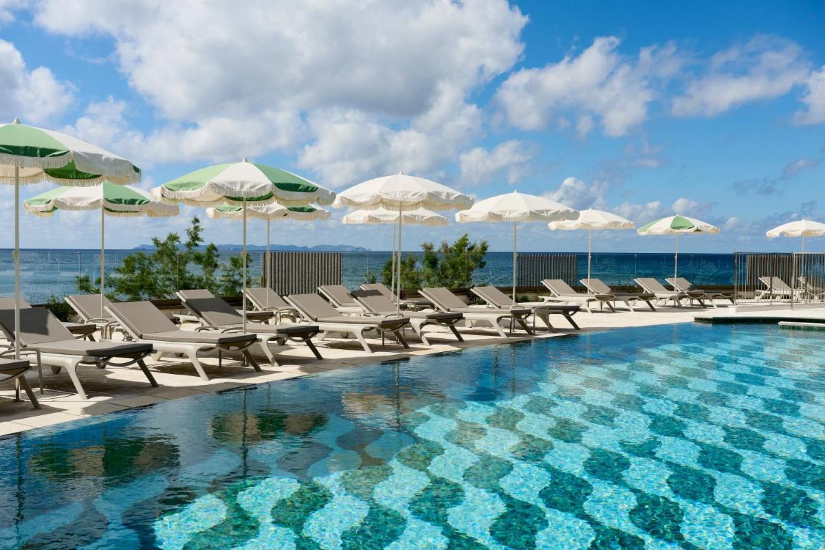 una piscina con tumbonas y sombrillas en Iberostar Selection Es Trenc -New Opening-, en Colonia de Sant Jordi