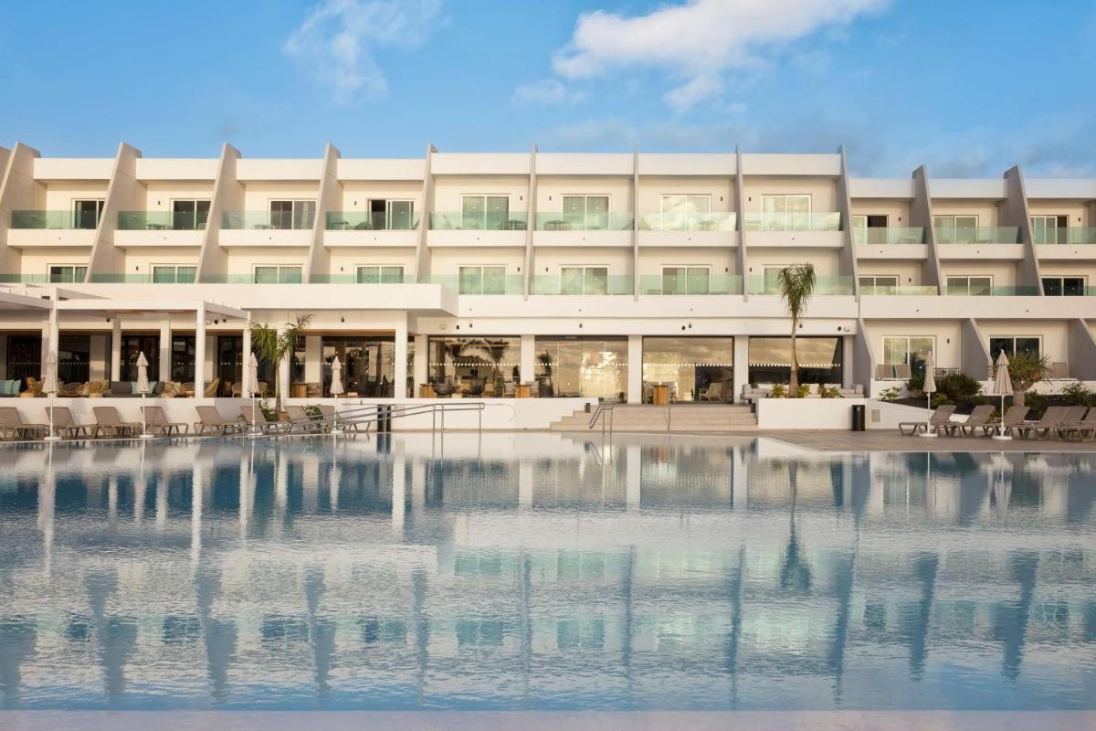 Un edificio con un estanque de agua enfrente. en Radisson Blu Resort, Lanzarote Adults Only, en Costa Teguise