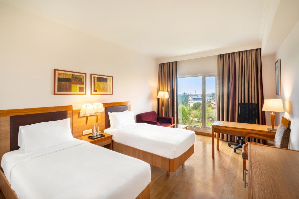 a hotel room with two beds and a desk at Park Plaza Chennai OMR in Chennai