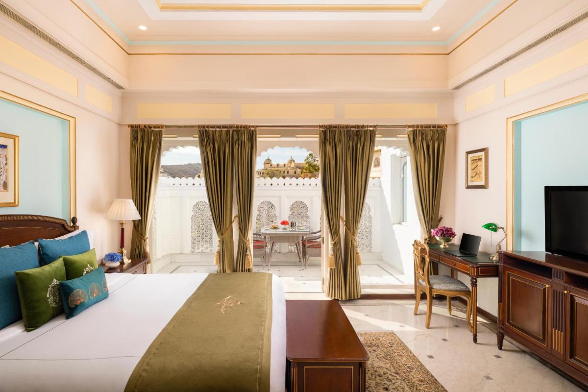 a bedroom with a bed and a desk and a television at Taj Fateh Prakash Palace Udaipur in Udaipur