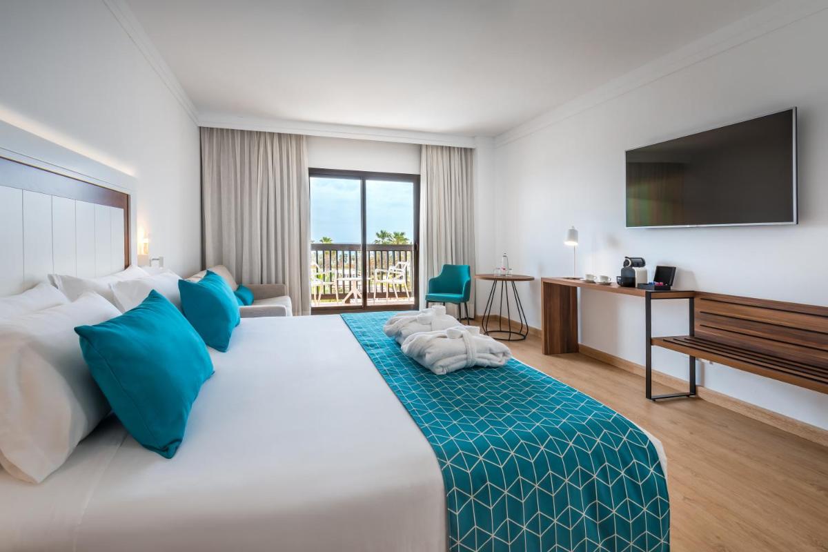 Una habitación de hotel con una cama grande con almohadas azules. en Barceló Cabo de Gata, en Retamar