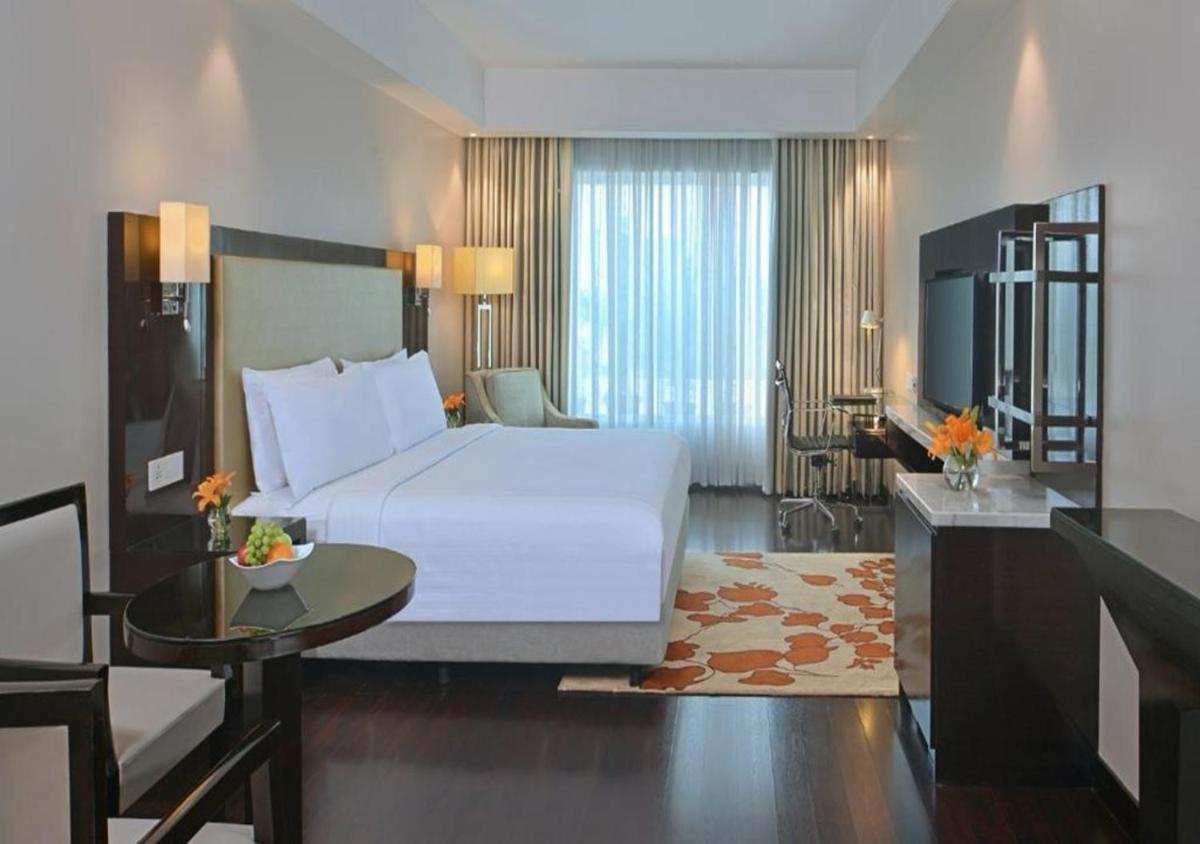 a bedroom with a large white bed and a table at Radisson Hotel Agra in Agra