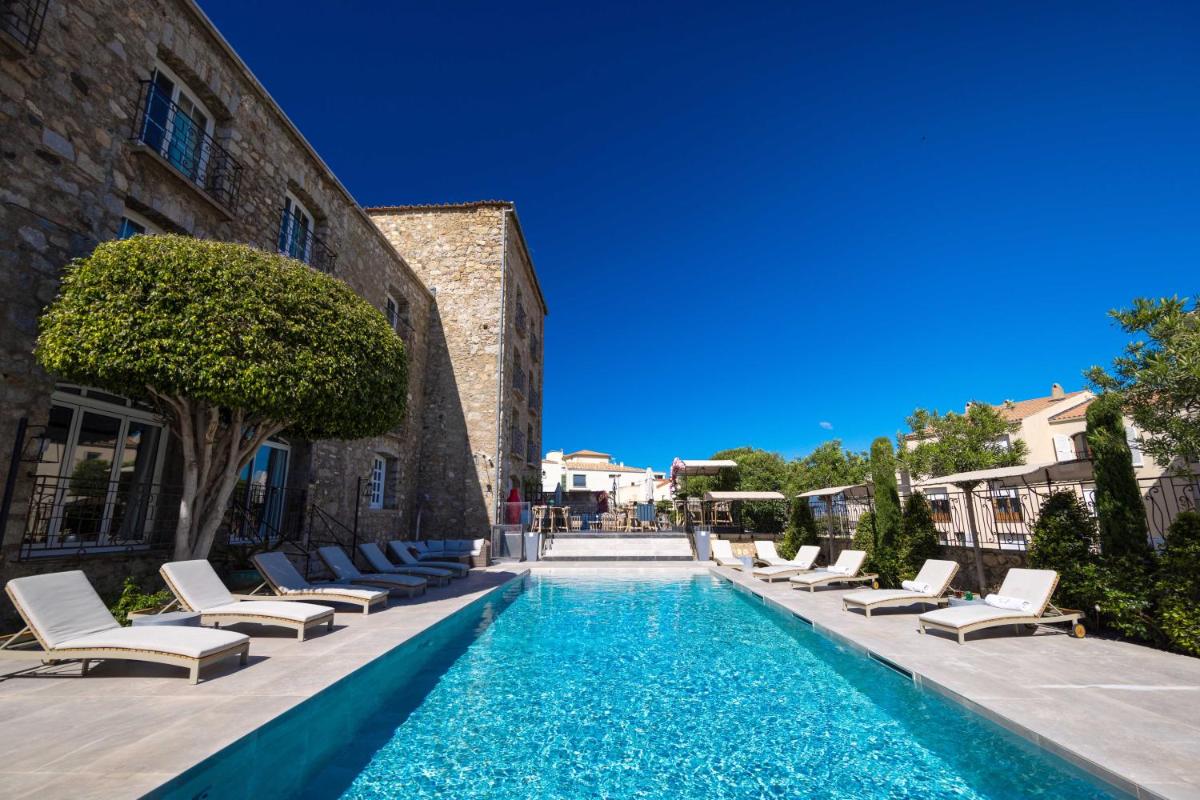 une piscine avec des chaises longues et une piscine dans l'établissement Hôtel L'Abbaye, à Calvi une piscine avec des chaises longues et une piscine dans l'établissement Hôtel L'Abbaye, à Calvi