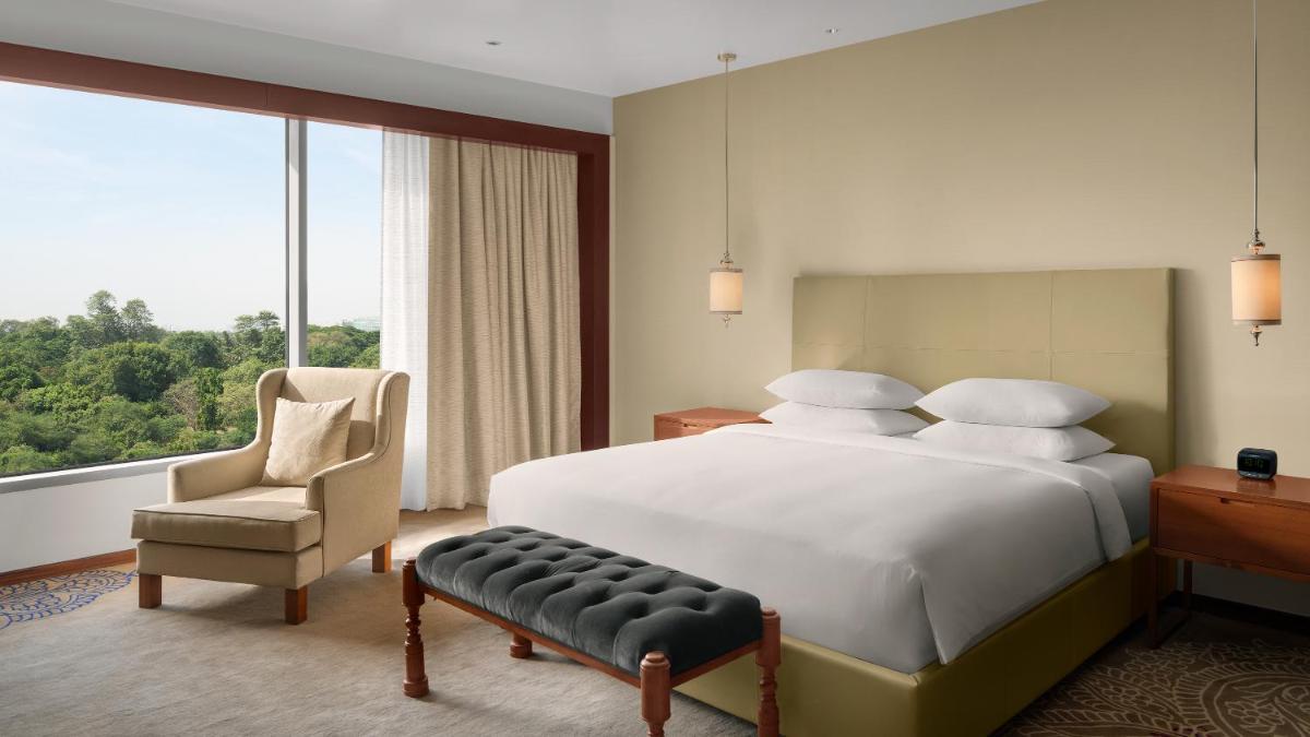 a bedroom with a white bed and a chair and a window at Park Hyatt Chennai in Chennai