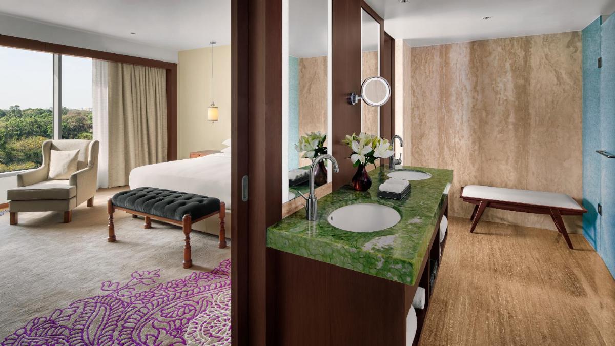 a hotel room with a bed and a bathroom with a sink at Park Hyatt Chennai in Chennai