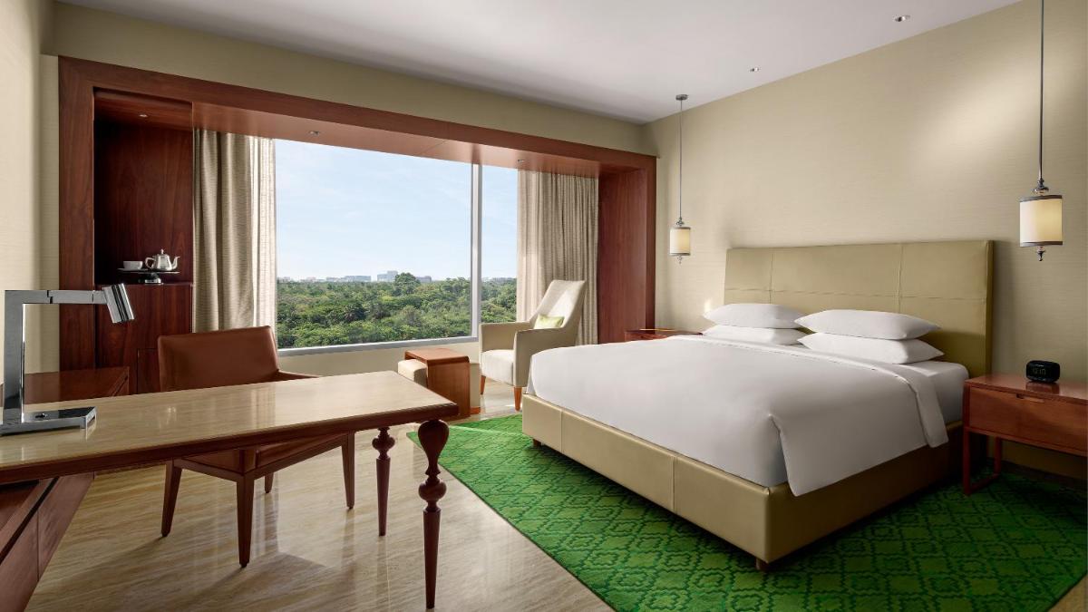 a bedroom with a bed and a desk and a window at Park Hyatt Chennai in Chennai