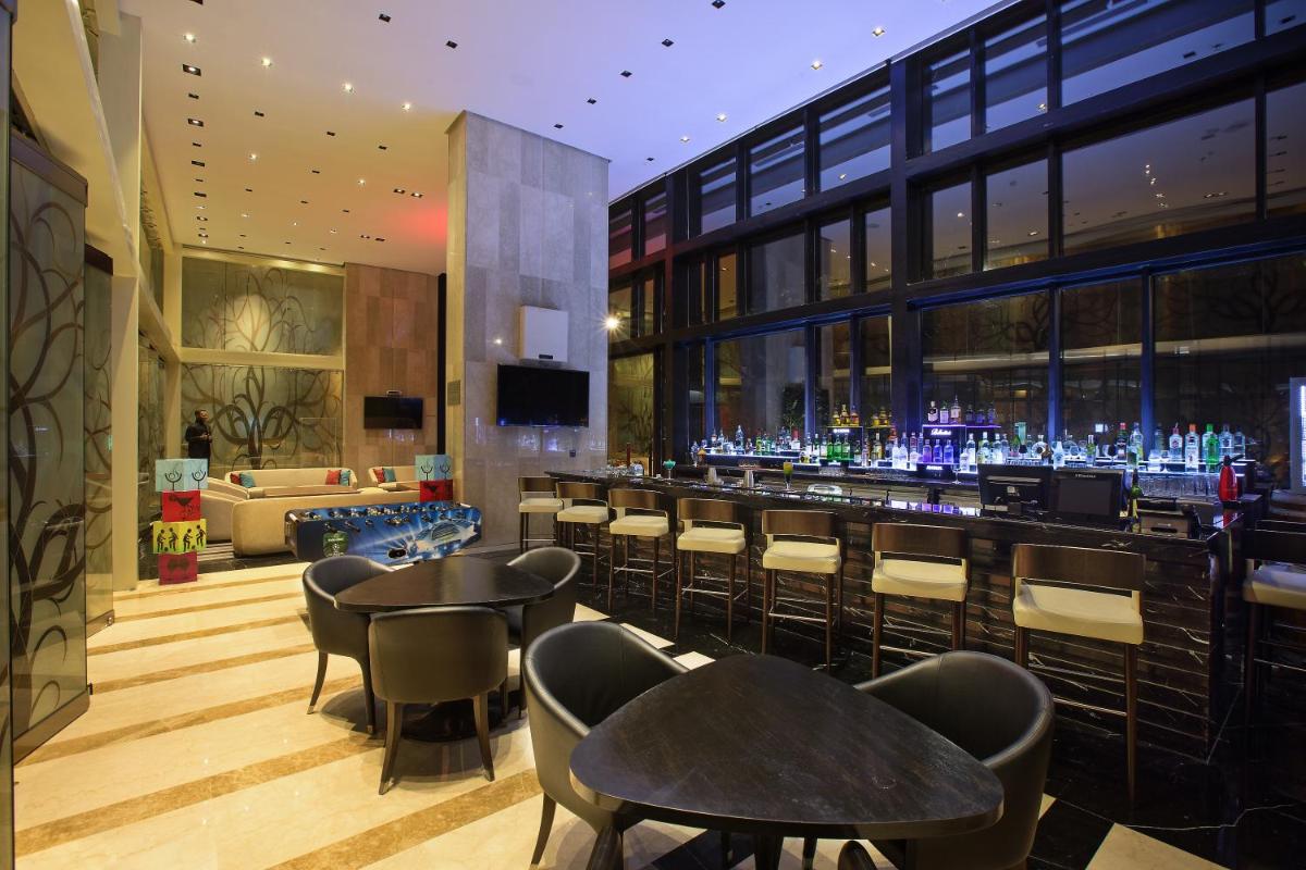 a bar with chairs and tables in a building at Novotel Kolkata Hotel and Residences in Kolkata a bar with chairs and tables in a building at Novotel Kolkata Hotel and Residences in Kolkata