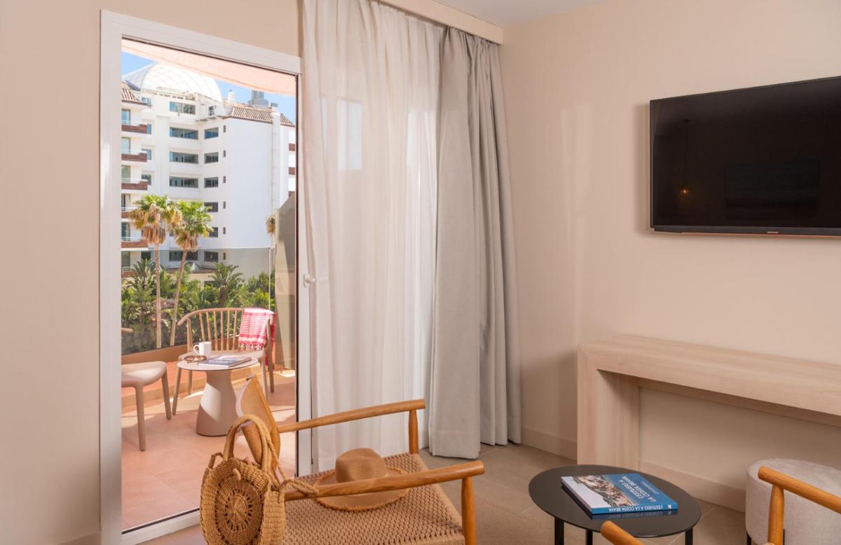Una sala de estar con chimenea y televisión. en AQUA Hotel The Breeze & Spa - All Inclusive - Adults Only - 4Sup, en Santa Susanna