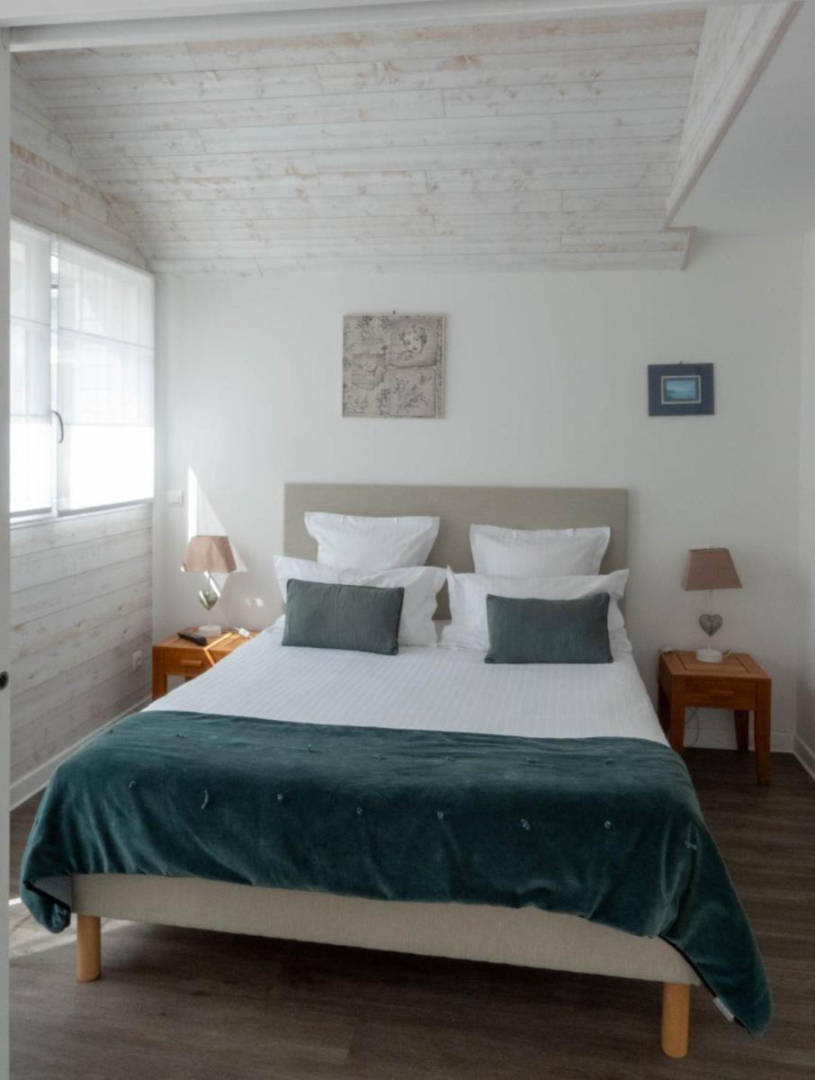 une chambre avec un grand lit blanc avec des draps verts dans l'établissement La Villa Bel Ange Hotel, à Saint-Philibert