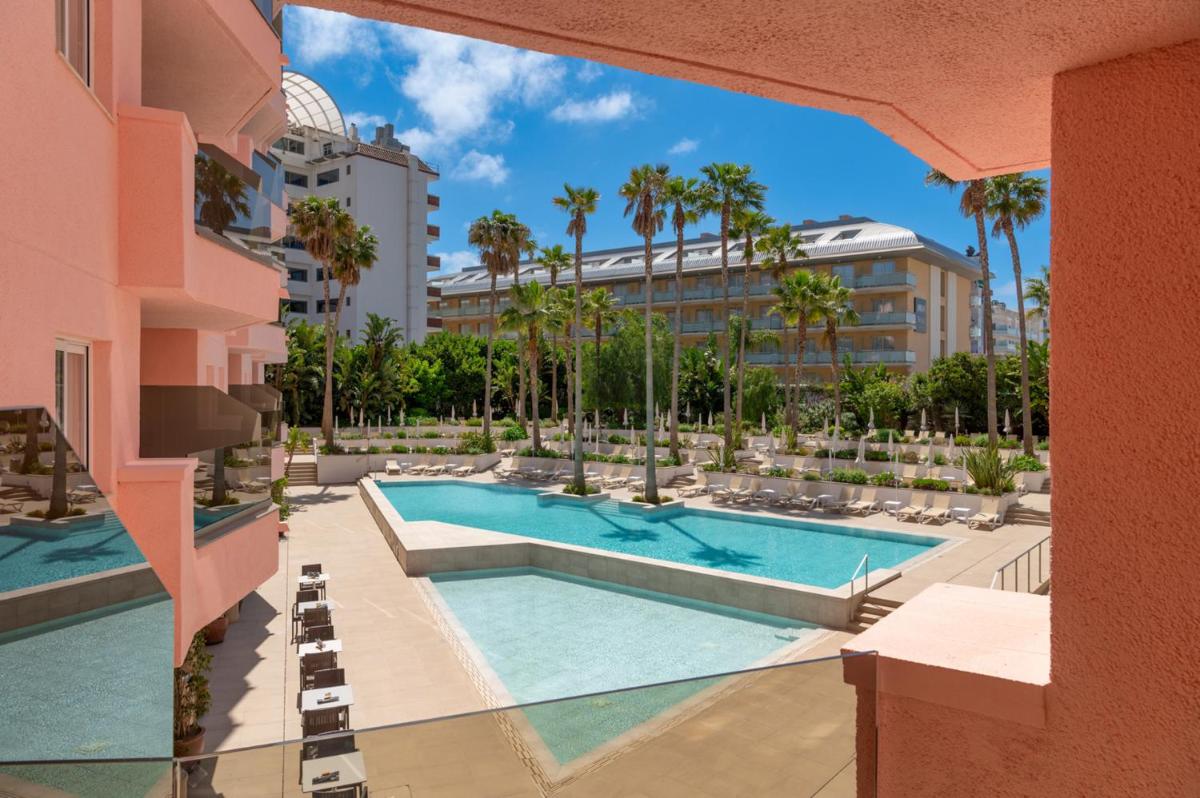 Una vista de la piscina en un resort con palmeras. en AQUA Hotel The Breeze & Spa - All Inclusive - Adults Only - 4Sup, en Santa Susanna