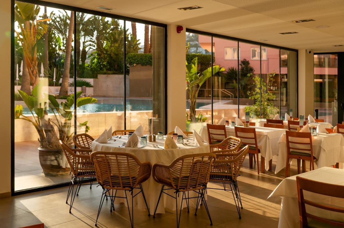 Un comedor con mesas y sillas y ventanas. en AQUA Hotel The Breeze & Spa - All Inclusive - Adults Only - 4Sup, en Santa Susanna