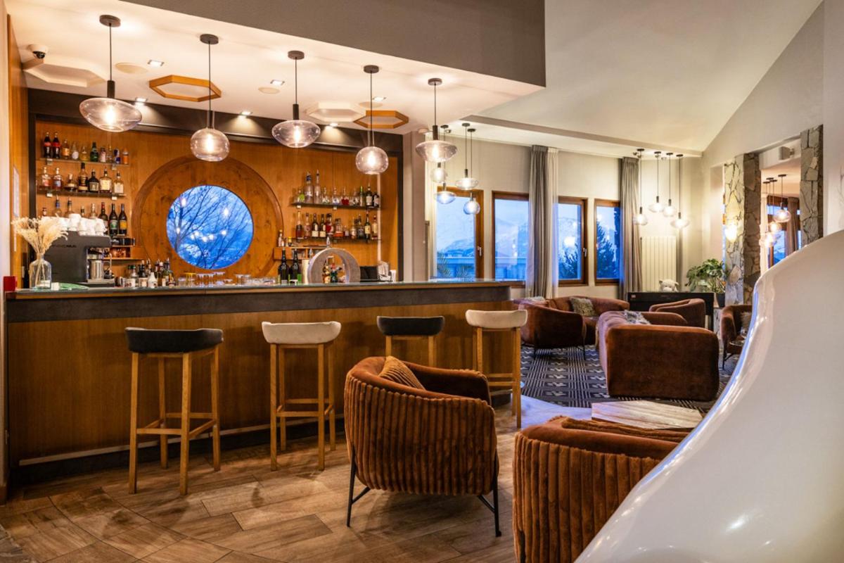 un bar dans un restaurant avec des chaises et des tables dans l'établissement Royal Ours Blanc Boutique Hôtel & Spa, à L'Alpe-d'Huez