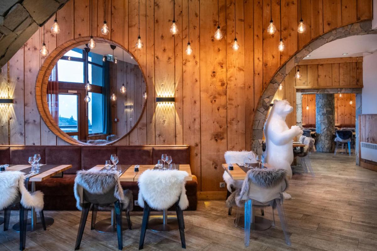un restaurant avec des tables et un miroir au mur dans l'établissement Royal Ours Blanc Boutique Hôtel & Spa, à L'Alpe-d'Huez