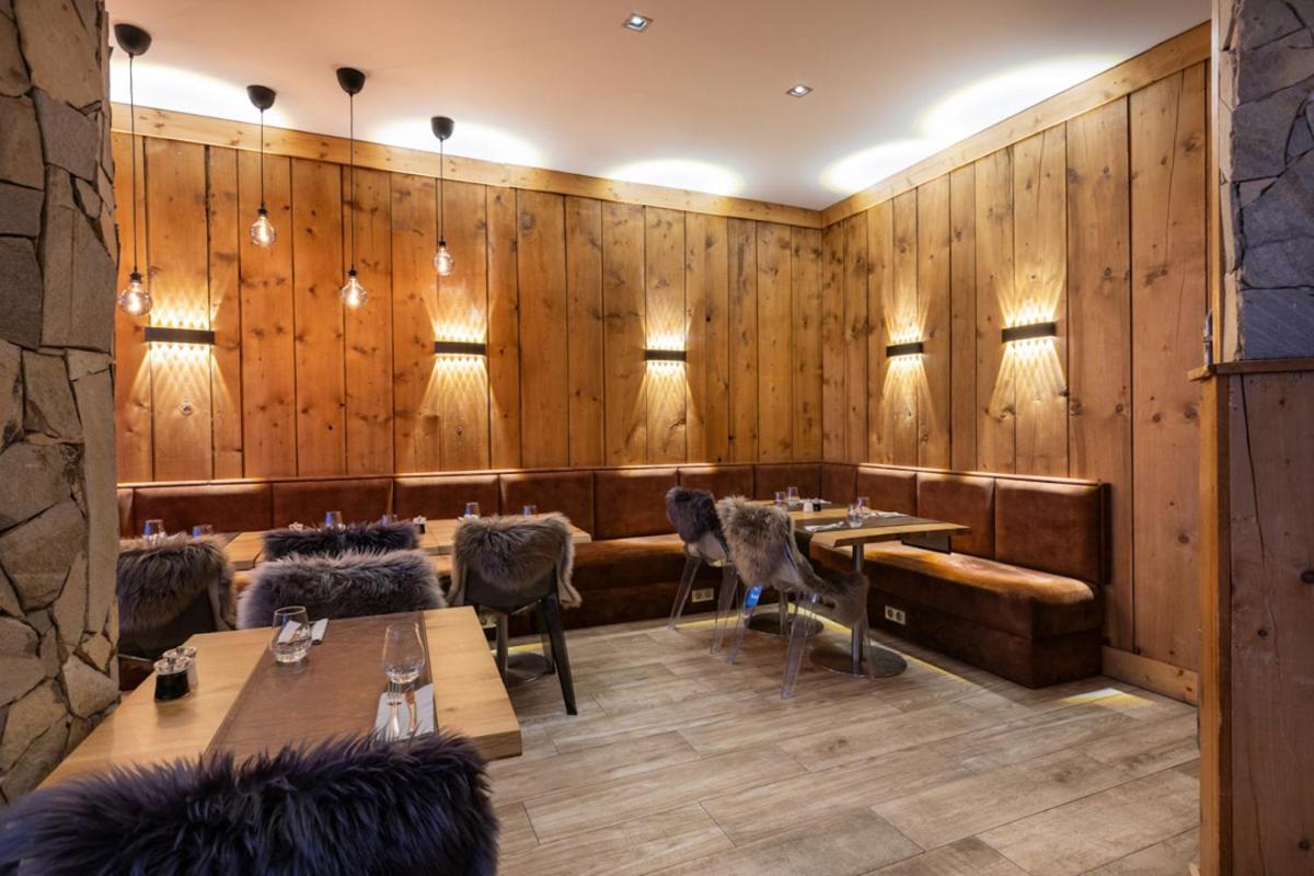un restaurant avec des murs en bois et des tables et chaises en bois dans l'établissement Royal Ours Blanc Boutique Hôtel & Spa, à L'Alpe-d'Huez 31 autres photos