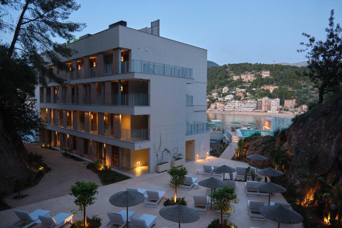 Un edificio con mesas y sombrillas delante. en Salino Port Soller, en Puerto de Sóller