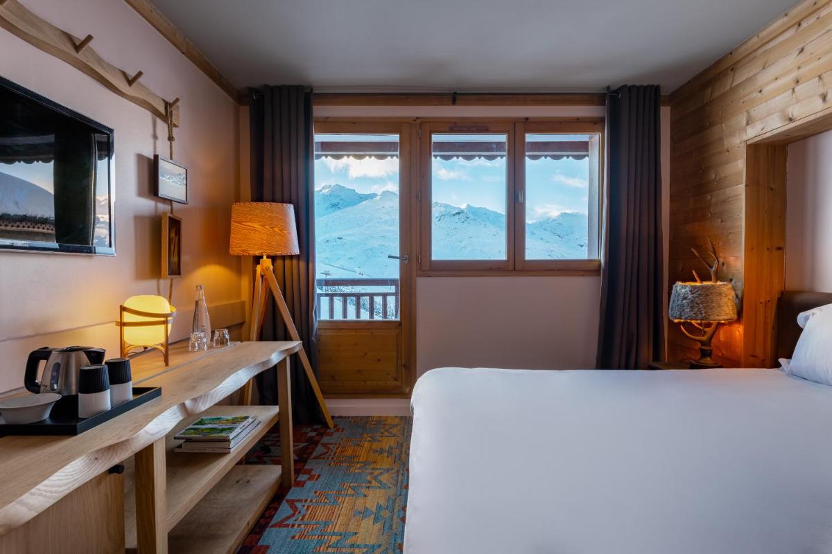 - une chambre avec un lit et une fenêtre donnant sur les montagnes dans l'établissement Chalet Hotel Kaya, aux Menuires 31 autres photos