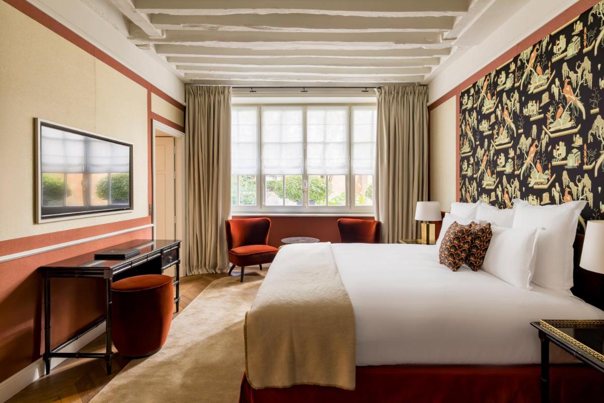 une chambre d'hôtel avec un grand lit et un bureau dans l'établissement Le Pavillon de la Reine & Spa, Place des Vosges, à Paris