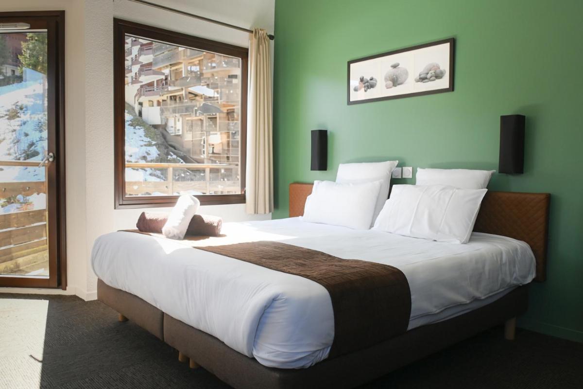 une chambre avec un grand lit avec une grande fenêtre dans l'établissement Hôtel Le Montana, à La Tania