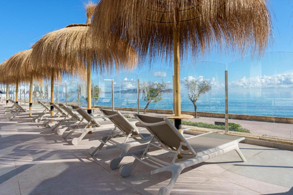 una fila de tumbonas bajo una sombrilla de paja en Ferrer Concord Hotel & Spa, en Can Picafort 82 fotos más