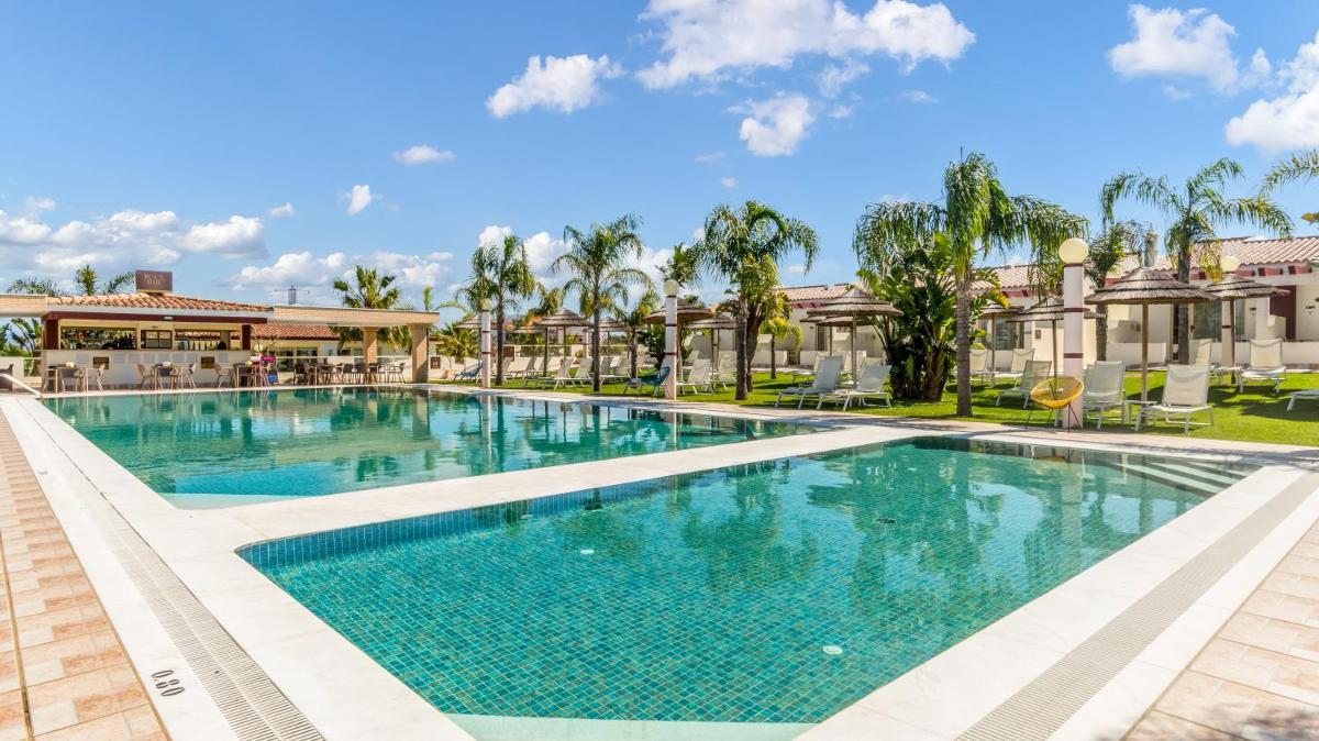 uma piscina em um resort com palmeiras em Hotel Rural Brícia Du Mar em Ferragudo