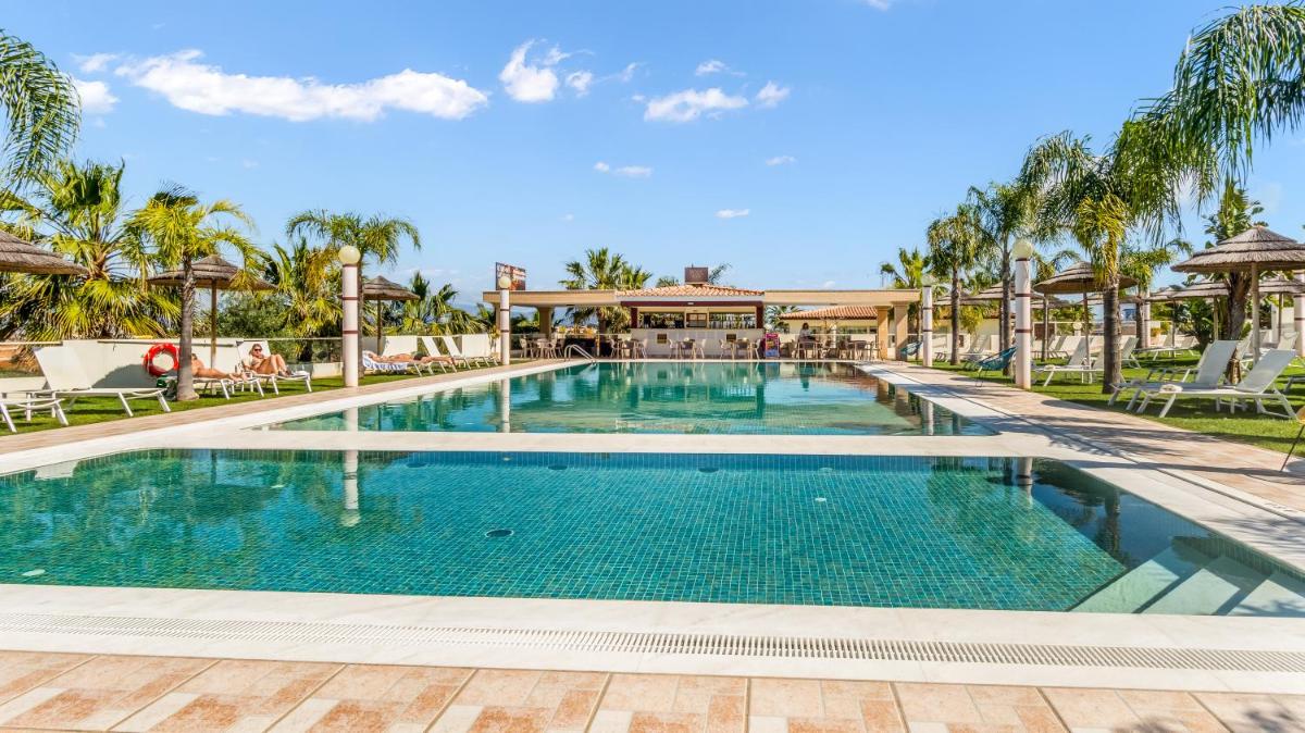 uma piscina em um resort com palmeiras em Hotel Rural Brícia Du Mar em Ferragudo