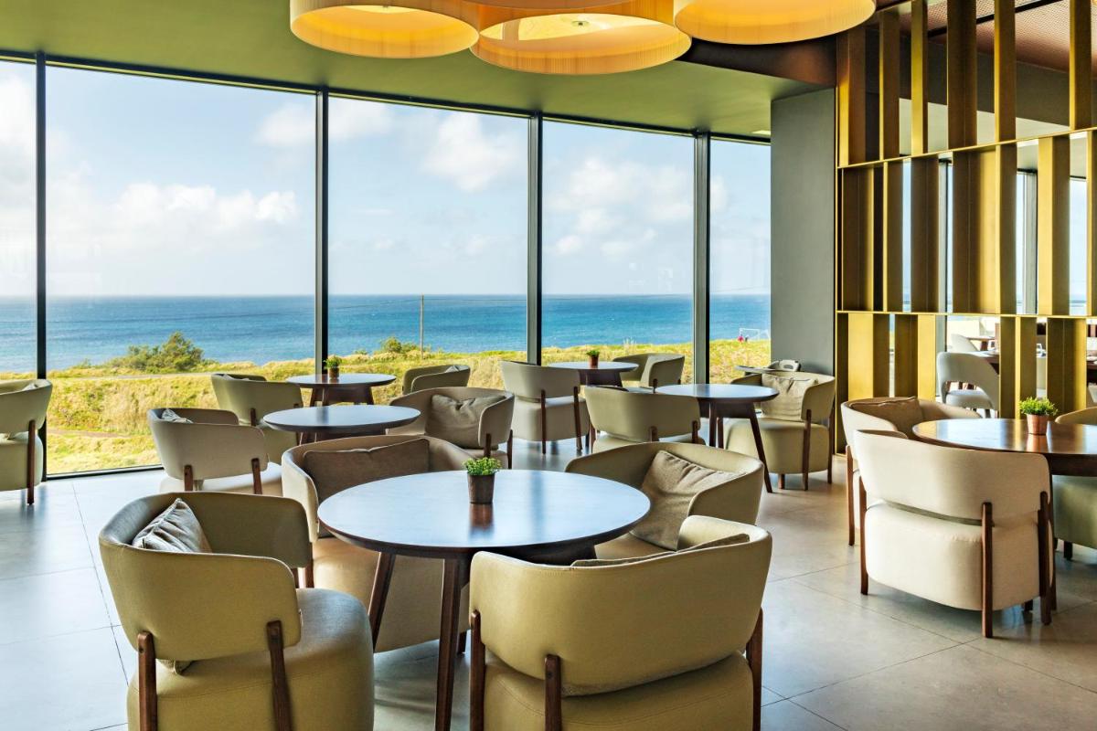 um restaurante com mesas e cadeiras e vista para o oceano em Hotel Verde Mar & SPA na Ribeira Grande