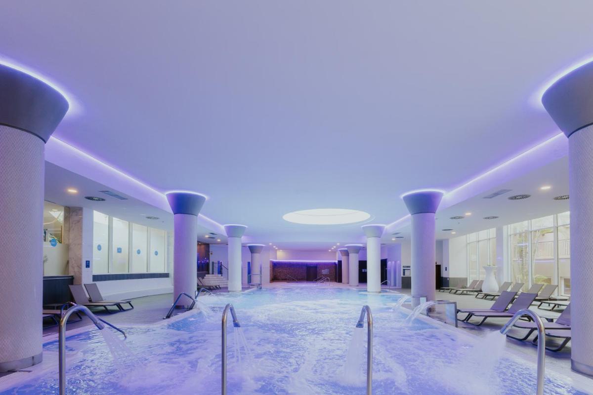 Una gran piscina con sillas en un edificio. en Landmar Costa los Gigantes Family Resort, en Puerto de Santiago