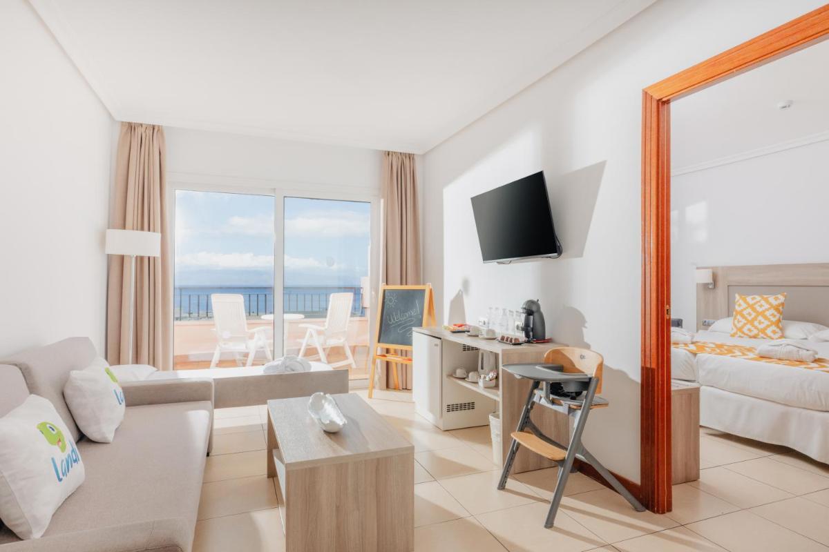 Una sala de estar con un sofá, una cama y una mesa. en Landmar Costa los Gigantes Family Resort, en Puerto de Santiago
