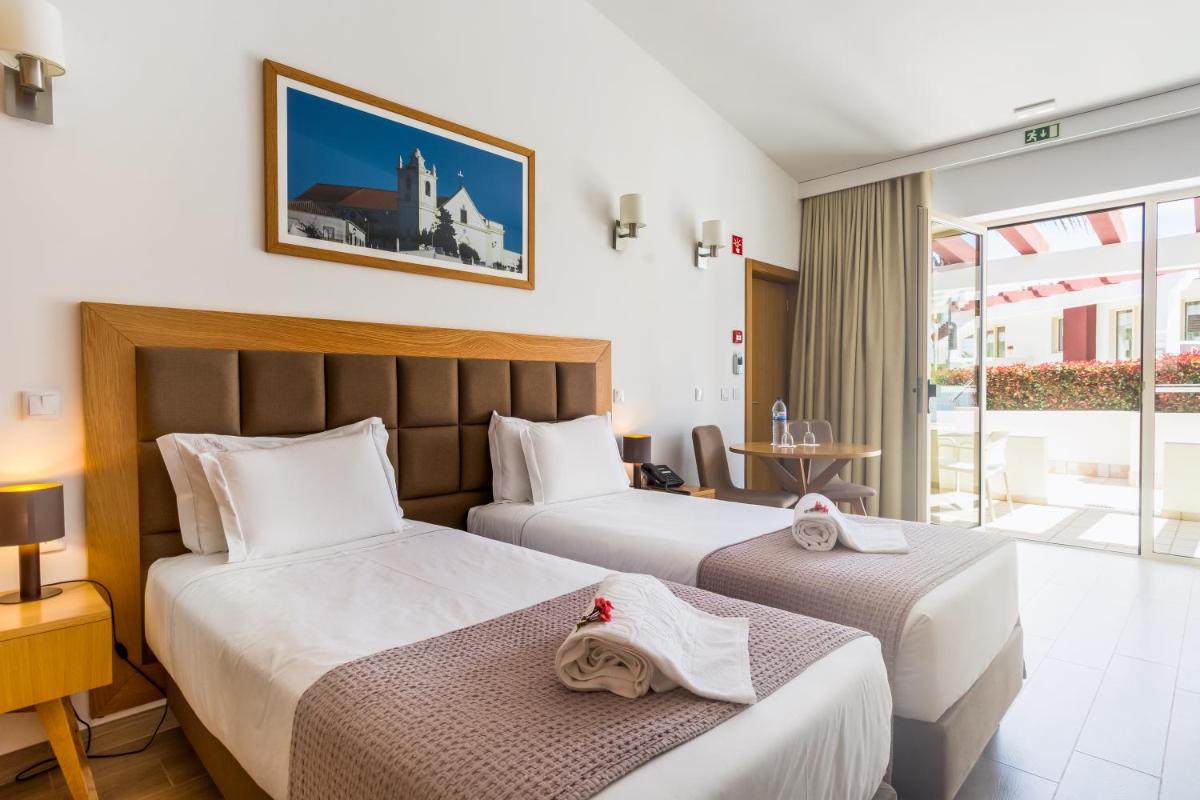 um quarto de hotel com duas camas e uma varanda em Hotel Rural Brícia Du Mar em Ferragudo mais 64 fotografias
