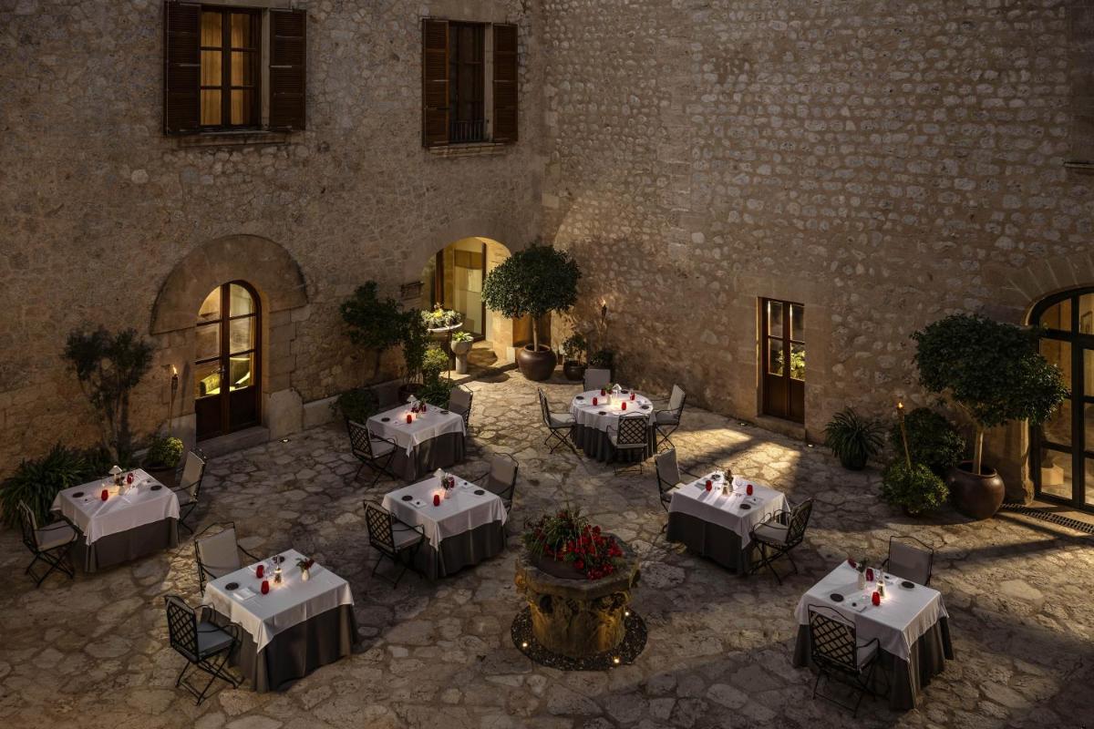 Un patio con mesas y sillas en un edificio. en Castell Son Claret - The Leading Hotels of the World, en Es Capdellà