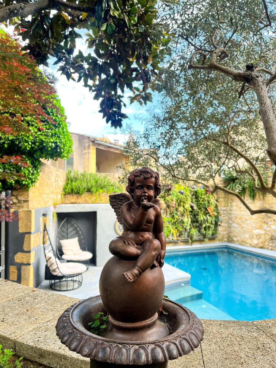 une statue d'une petite fille assise sur un ballon à côté d'une piscine dans l'établissement Le Castellas Hotel & SPA - TERITORIA, à Collias