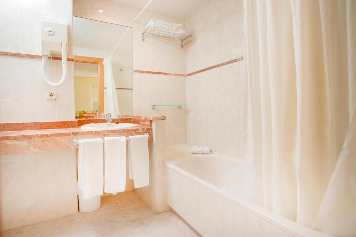 Un baño blanco con bañera y lavabo. en Hotel Tres Anclas, en Gandía
