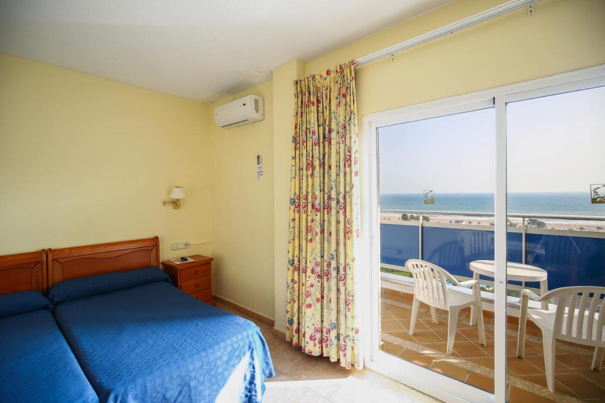 Un dormitorio con una cama y vista al mar. en Hotel Tres Anclas, en Gandía