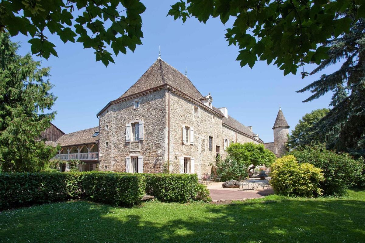 un ancien bâtiment en pierre avec une tourelle sur une pelouse dans l'établissement Château de Fleurville & Spa, à Fleurville