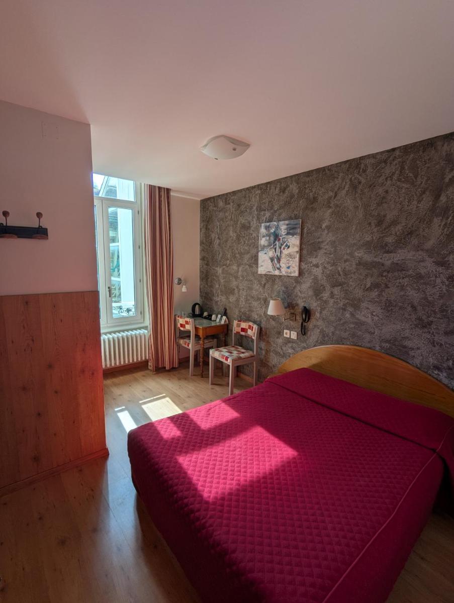 - une chambre avec un lit rouge et une table dans l'établissement Logis Hôtel Regina, à La Bourboule