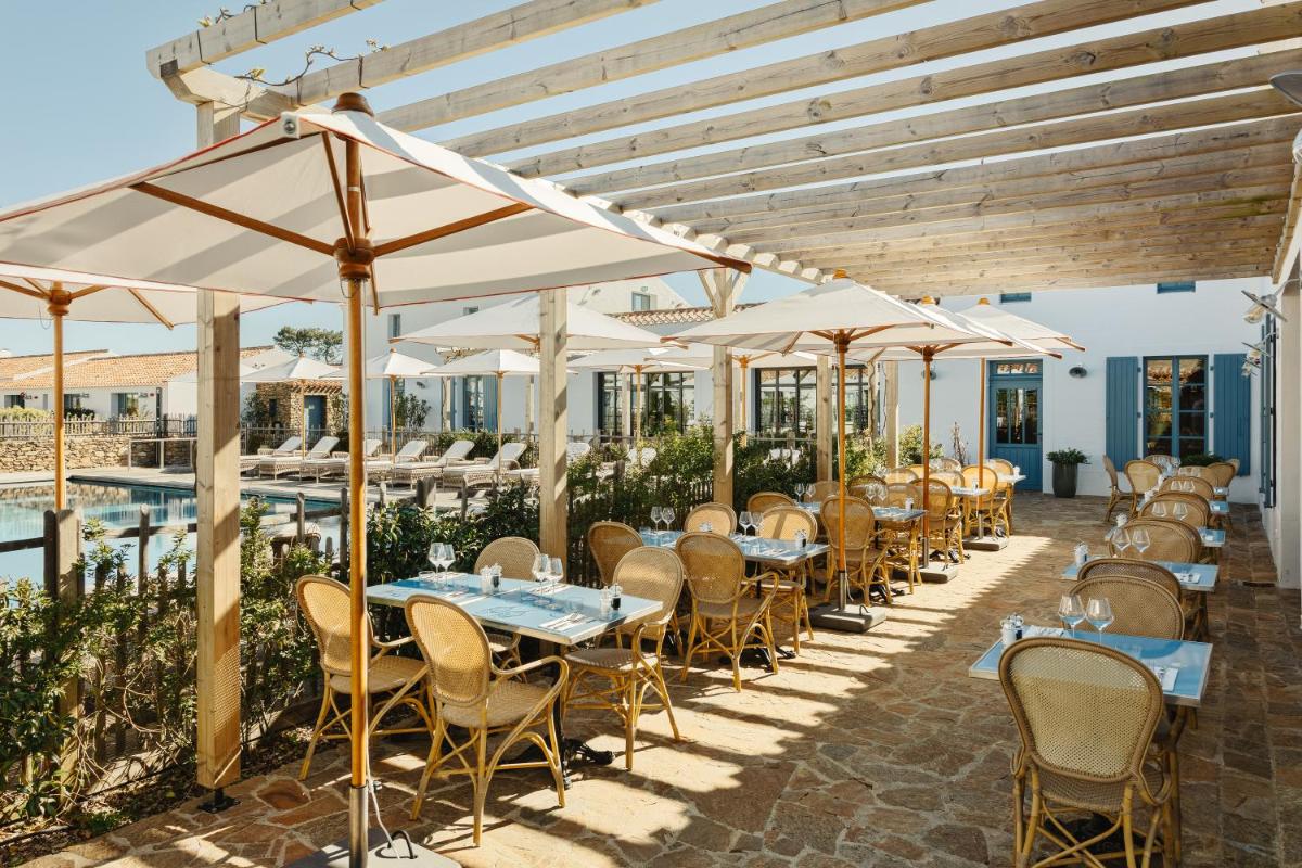 - une rangée de tables et de chaises sous des parasols dans un restaurant dans l'établissement La Mission Hôtel & SPA - l'île d'Yeu, à L'Ile d'Yeu