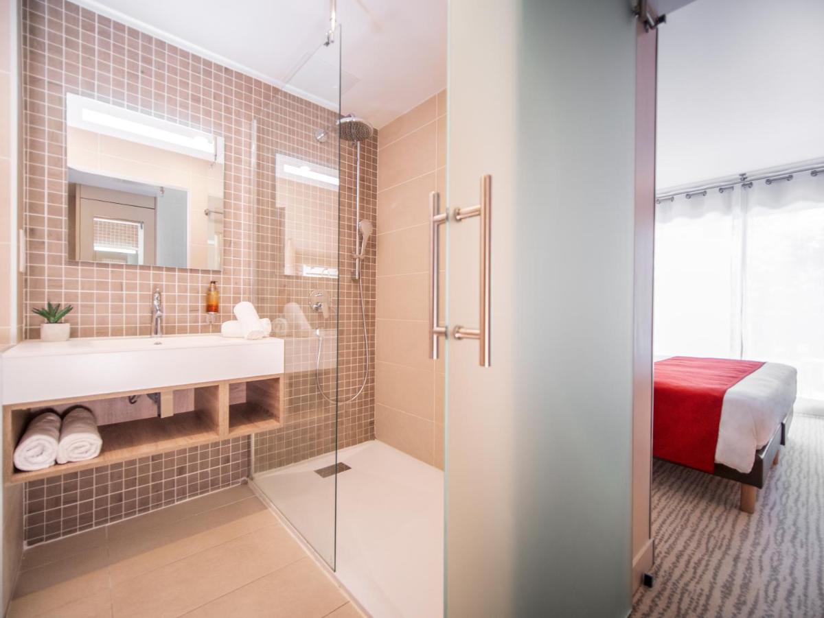 une salle de bain avec douche et lavabo dans l'établissement Hôtel & Spa Vitalparc, The Originals Collection, à Lacanau-Océan