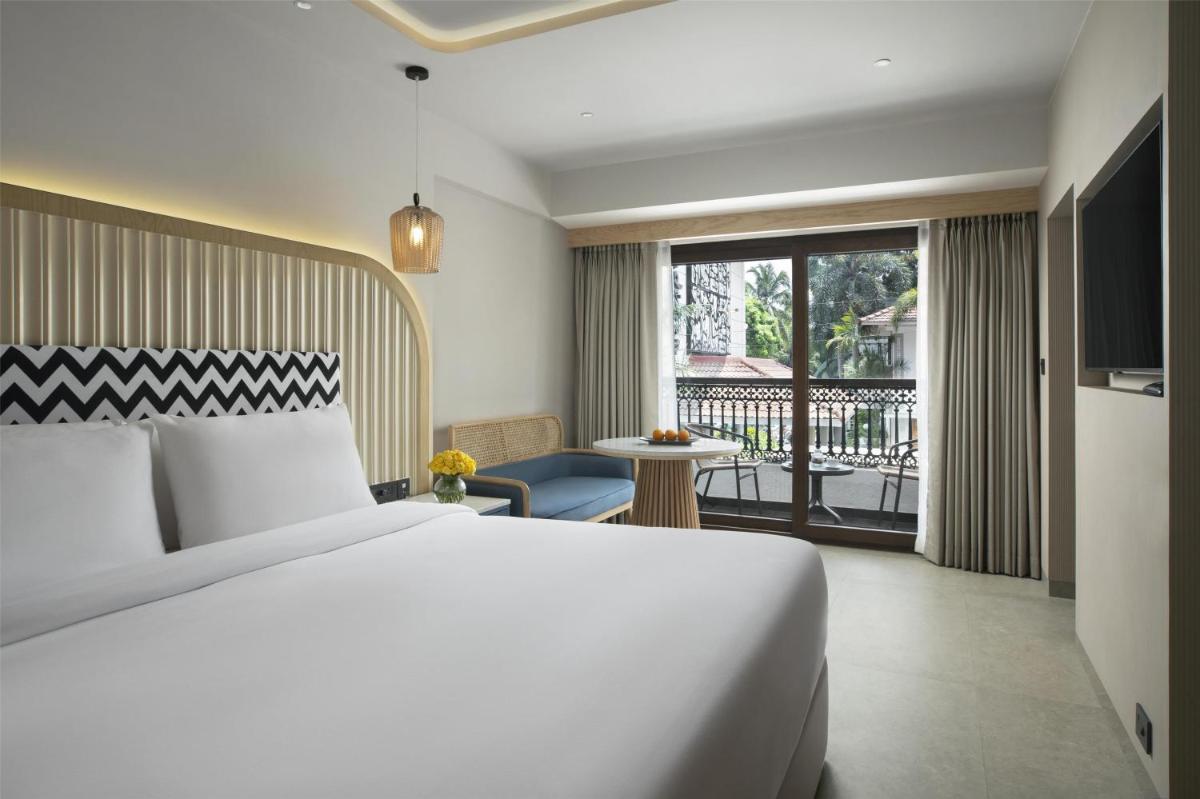 a hotel room with a bed and a balcony at Radisson Goa Candolim in Candolim