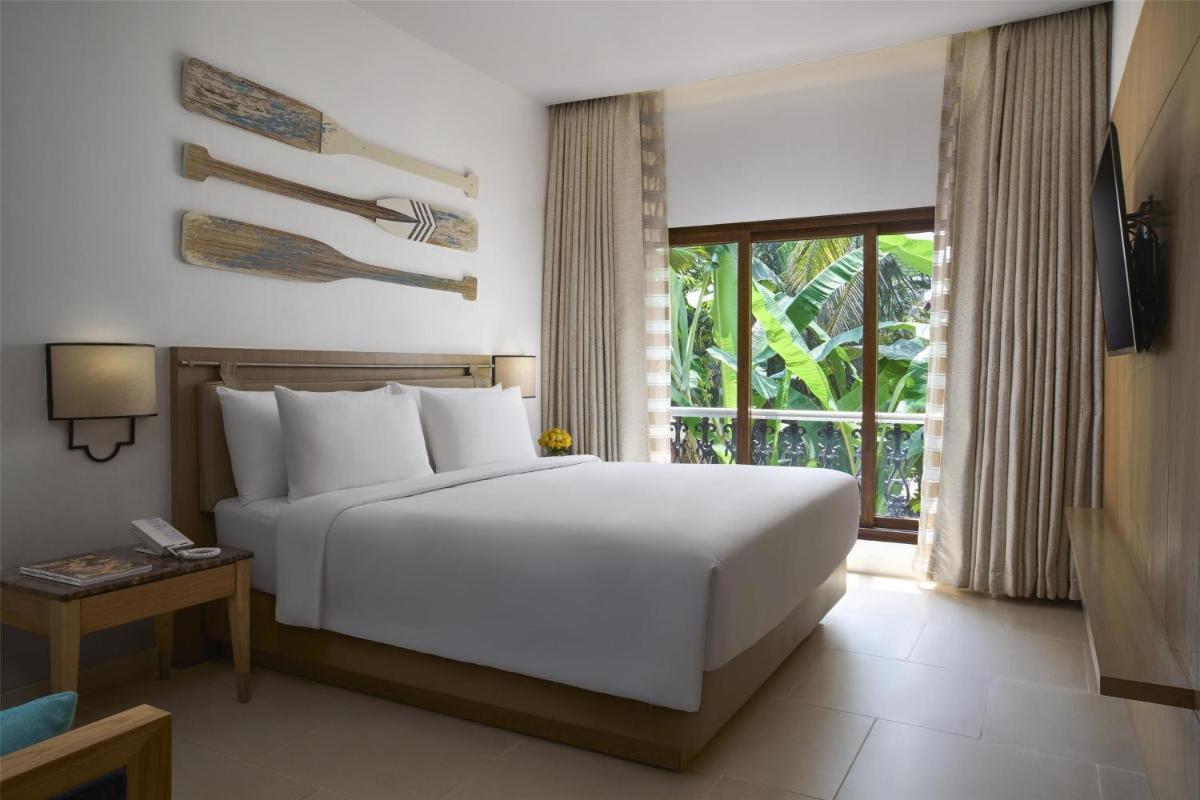 a bedroom with a white bed and a window at Radisson Goa Candolim in Candolim