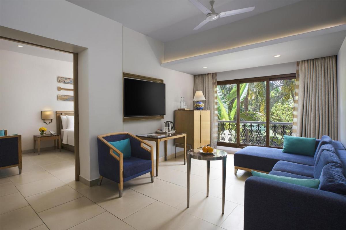 a living room with a blue couch and a tv at Radisson Goa Candolim in Candolim