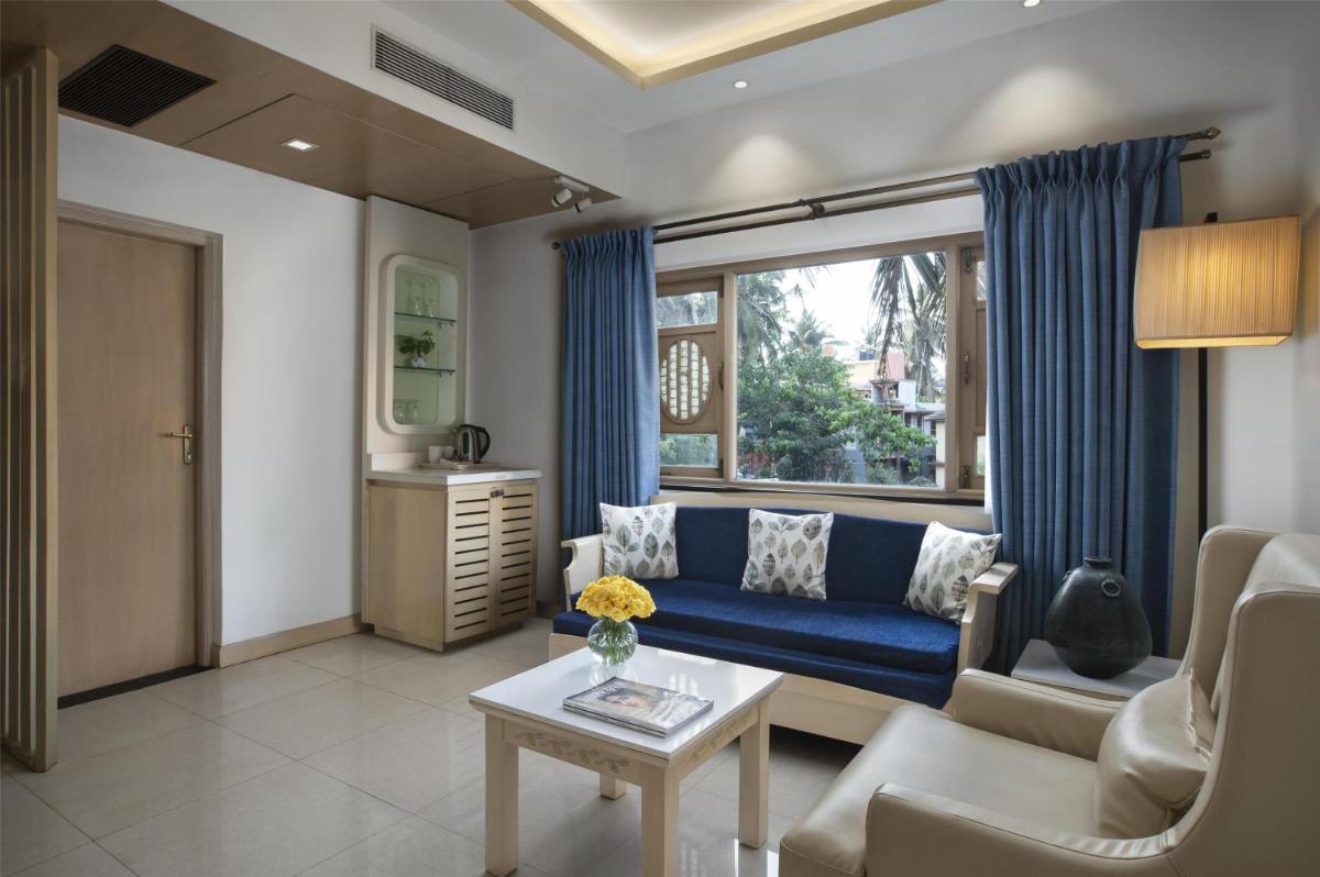 a living room with a blue couch and a window at Radisson Goa Candolim in Candolim