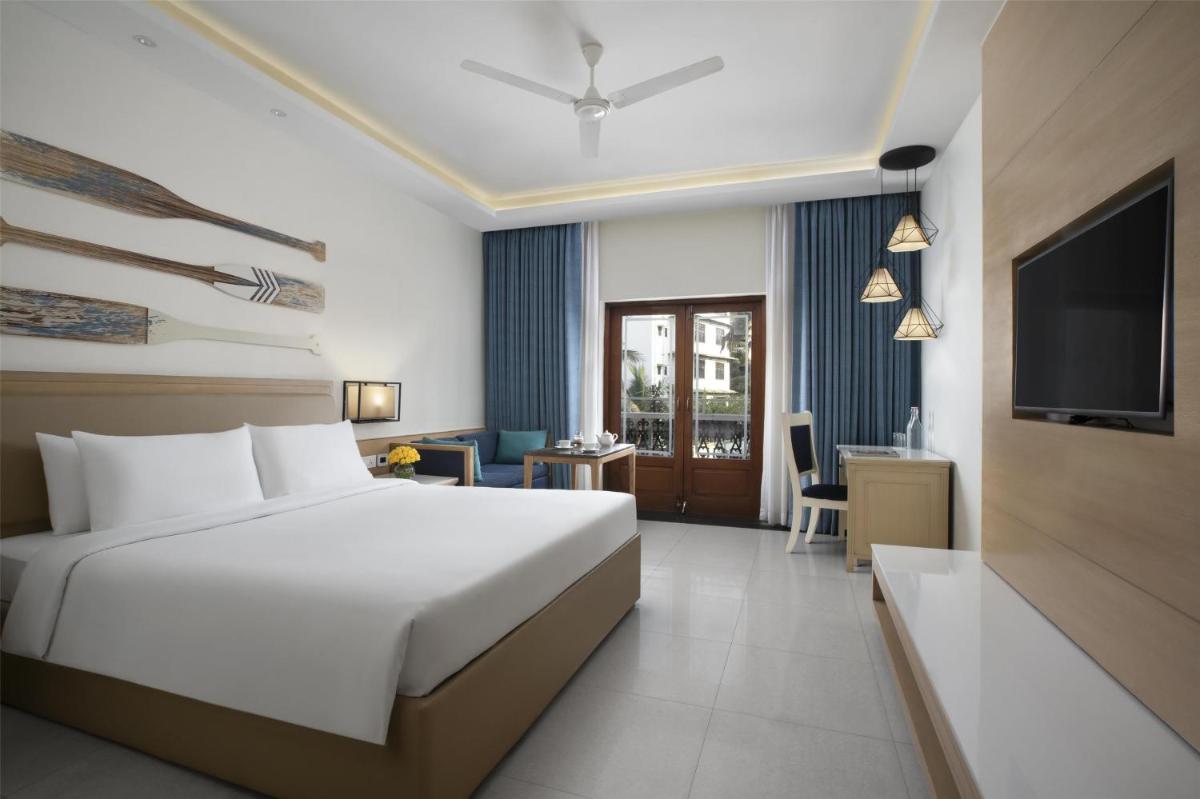 a hotel room with a bed and a television at Radisson Goa Candolim in Candolim