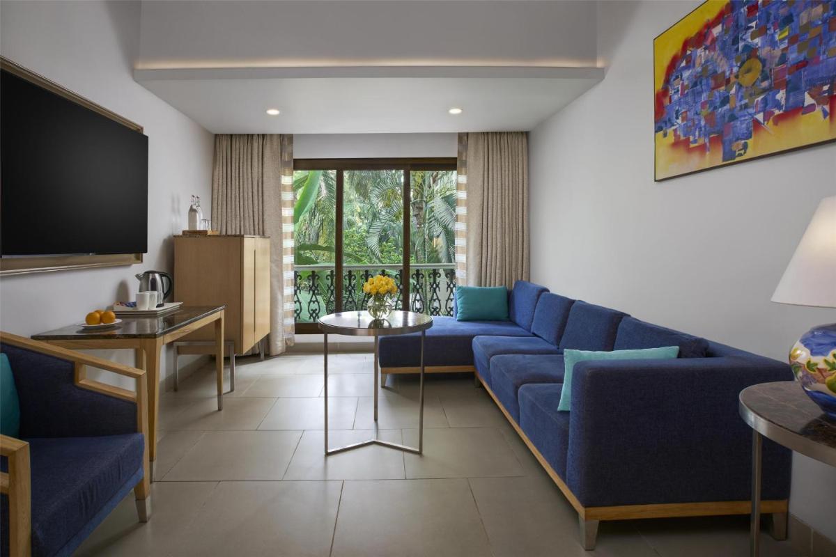 a living room with a blue couch and a tv at Radisson Goa Candolim in Candolim