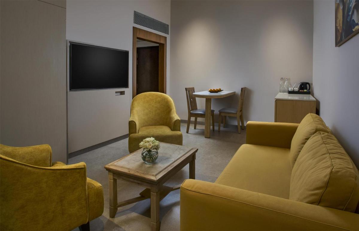 a living room with yellow chairs and a tv at Radisson Goa Candolim in Candolim