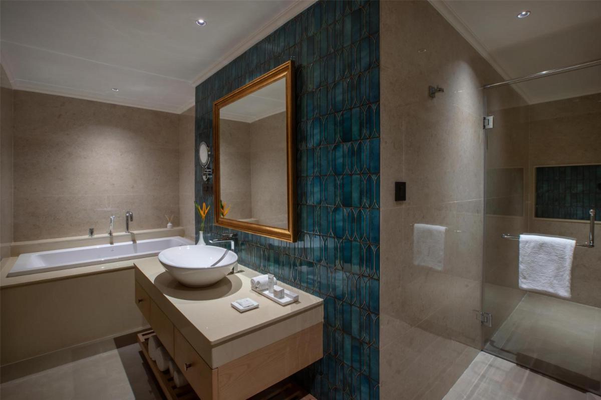 a bathroom with a sink and a mirror and a tub at Radisson Goa Candolim in Candolim