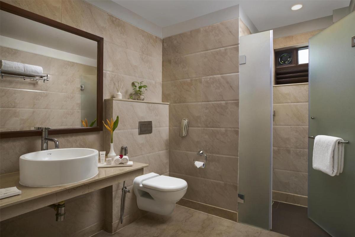 a bathroom with a toilet and a sink and a mirror at Radisson Goa Candolim in Candolim