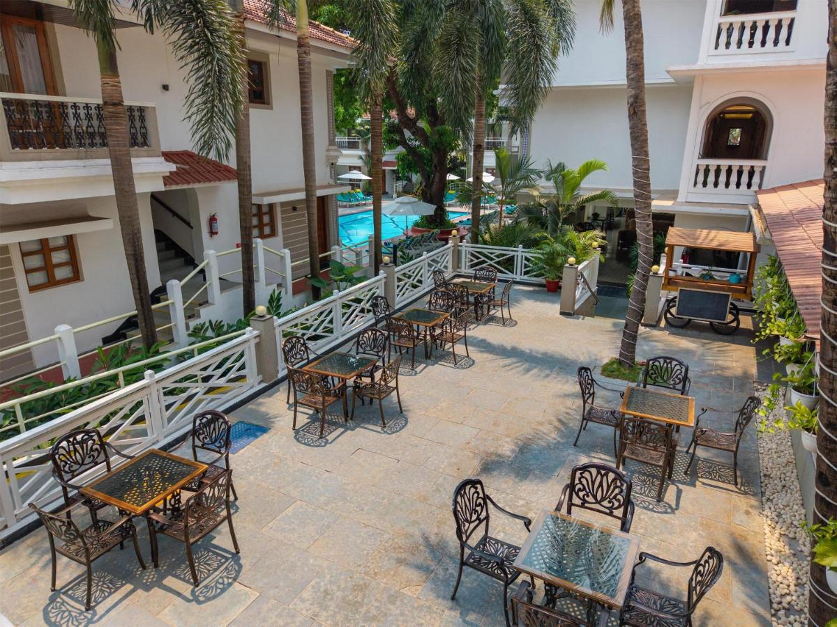 an outdoor patio with tables and chairs and a pool at Radisson Goa Candolim in Candolim