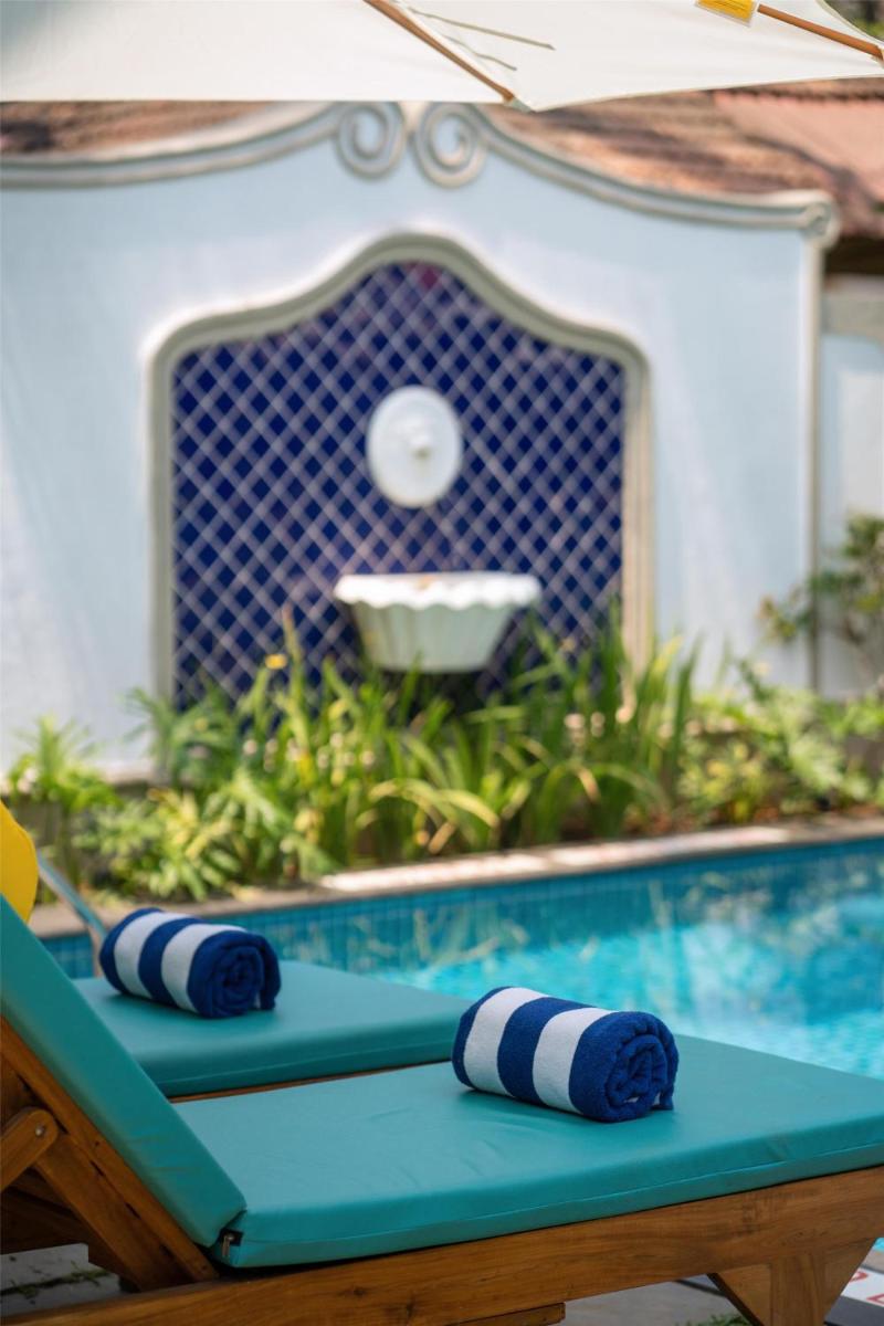 a table with blue and white pillows sitting next to a swimming pool at Radisson Goa Candolim in Candolim